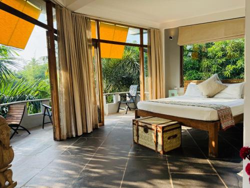 a bedroom with a bed and a balcony with windows at Casa Da Praia in Candolim