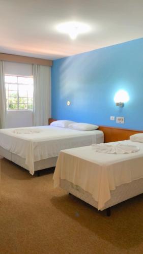 two beds in a room with blue walls at HOTEL VILLA QUATI CENTRO in Foz do Iguaçu