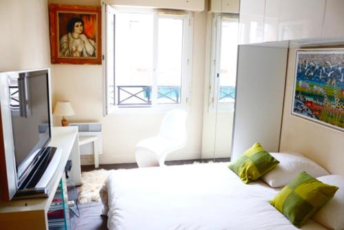 um quarto com uma cama, uma televisão e uma janela em Heart of Paris - Entire or Private Room Apartment - Bastille & Marais em Paris
