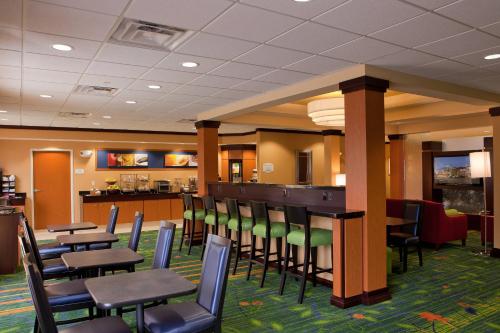 a restaurant with tables and chairs and a bar at Fairfield Inn and Suites Flint Fenton in Fenton
