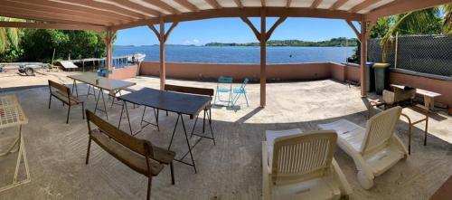 a patio with chairs and a table with a view of the water at Maison exurville in Le Robert