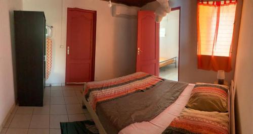 a bedroom with a bed and a red door at Maison exurville in Le Robert