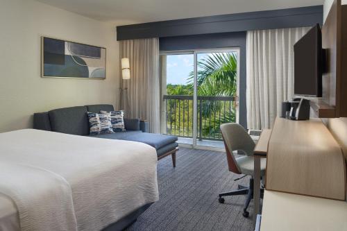 a hotel room with a bed and a desk with a computer at Courtyard by Marriott Fort Lauderdale Weston in Weston