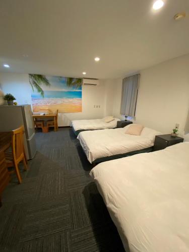 a hotel room with three beds and a table at MR TOMO FUJI in Fuji