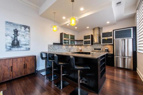 a kitchen with a black island with bar stools at Luxe Louisville Condo~King BR~Near YUM Center in Louisville