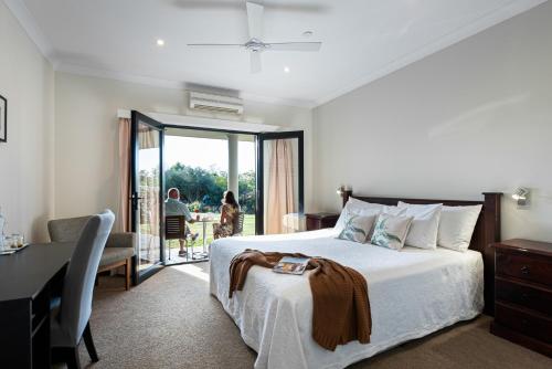 a bedroom with a bed and a desk and a balcony at Mudgee Guesthouse in Mudgee