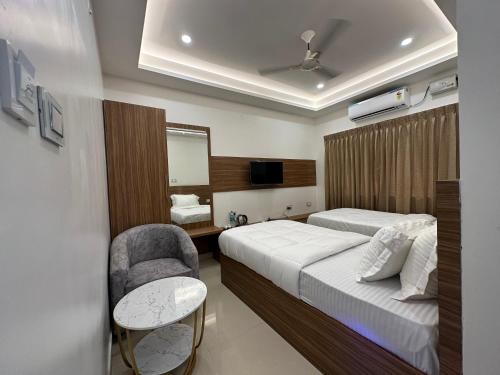 una habitación de hotel con 2 camas y una silla en SRI KRISHNA RESIDENCY en Tiruchchirāppalli