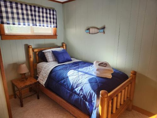 Schlafzimmer mit einem Bett mit blauer Bettwäsche und einem Fenster in der Unterkunft The White Conifer Cabin 