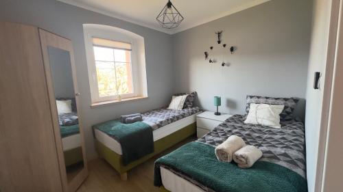 a small bedroom with two beds and a window at Sasanka LZ in Lądek-Zdrój