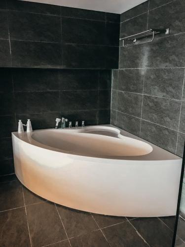 a bath tub in a bathroom with black tiles at Luxury Pentstudio Westlake - Tay Ho, Ha Noi in Hanoi