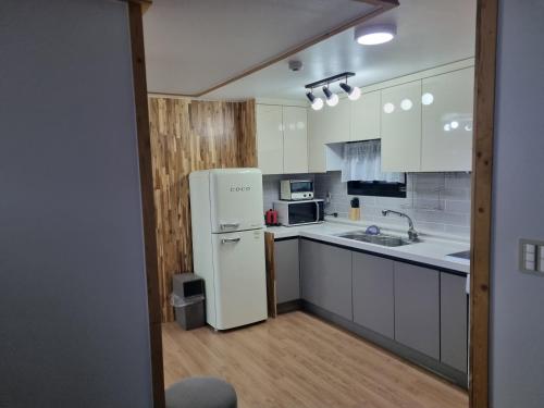 Una cocina con electrodomésticos blancos y un refrigerador blanco. en JEJU Amoje, en Seogwipo