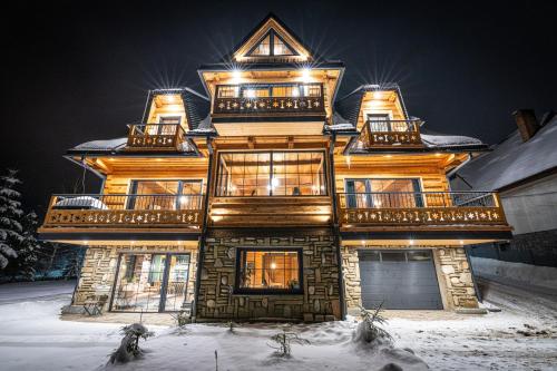 a large wooden house in the snow at night at Nowy Szlak in Kościelisko