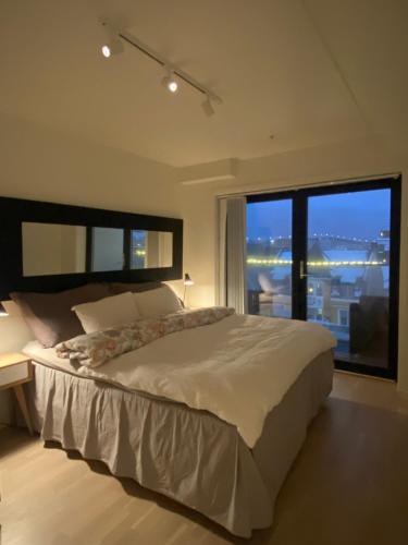 een slaapkamer met een groot bed en een groot raam bij The Heart of Tromsø city Apartment in Tromsø