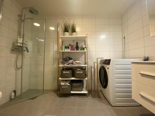 a bathroom with a shower and a washing machine at The Heart of Tromsø city Apartment in Tromsø