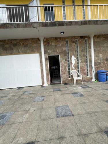 un edificio con una puerta de garaje blanca y una silla en Hostel Encanto de Mongaguá en Mongaguá