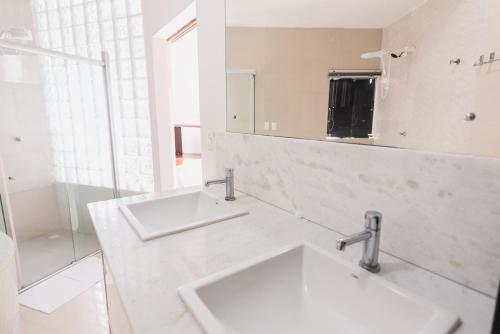 a white bathroom with two sinks and a mirror at Cobertura exclusiva em ponta negra com vista para o mar in Natal