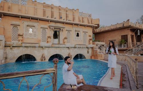 a man and a woman standing next to a pool at Ajit Bhawan - A Palace Resort in Jodhpur