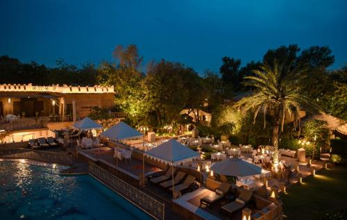 an outdoor restaurant with tables and umbrellas at night at Ajit Bhawan - A Palace Resort in Jodhpur