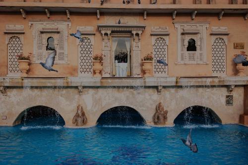 a building with two pigeons flying over a fountain at Ajit Bhawan - A Palace Resort in Jodhpur