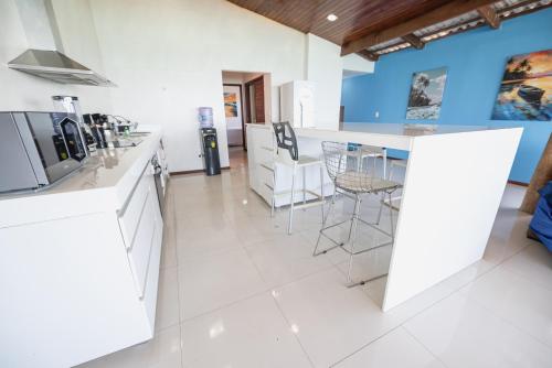 a kitchen with white appliances and a counter with stools at Cobertura exclusiva em ponta negra com vista para o mar in Natal