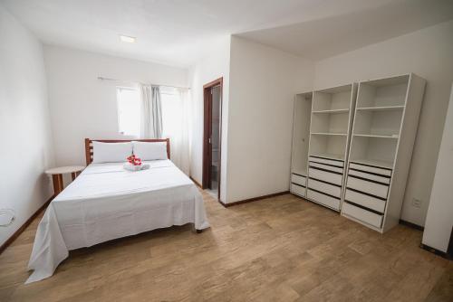 a bedroom with a white bed and a large closet at Cobertura exclusiva em ponta negra com vista para o mar in Natal