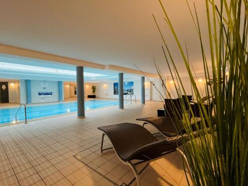 a hotel lobby with a swimming pool and a chair at Villanelle - Spa & Meer in Büsum