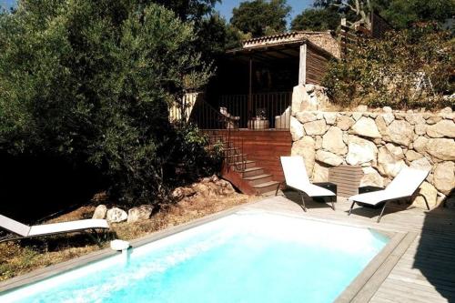 uma piscina com duas cadeiras e uma casa em La Bergerie Nepita avec piscine pour 4 pers. em Porto-Vecchio