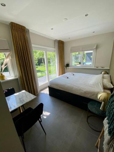 um quarto com uma cama, uma mesa e janelas em Noflik Heerenveen em Heerenveen