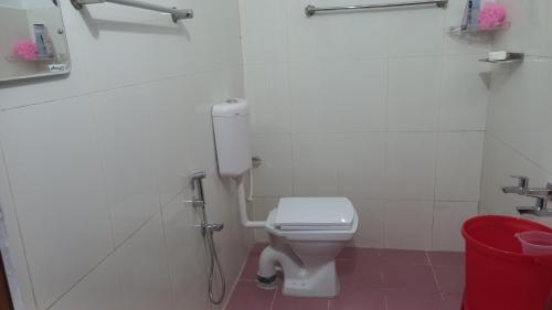 a bathroom with a white toilet and a red trash can at Niks home stay -C in Trichūr