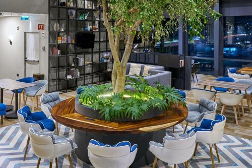 a table with a tree in the middle of a lobby at City Express Plus by Marriott Ensenada in Ensenada