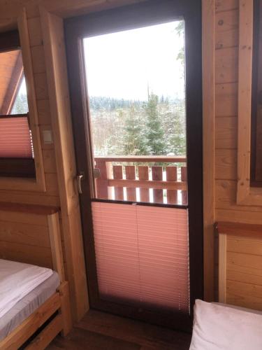 Habitación con puerta corredera de cristal y balcón. en Zaśnieżony Domek przy Dolinie Chochołowskiej, en Witów