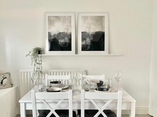 a white dining room table with two white chairs at Windsor Cottage in Amble