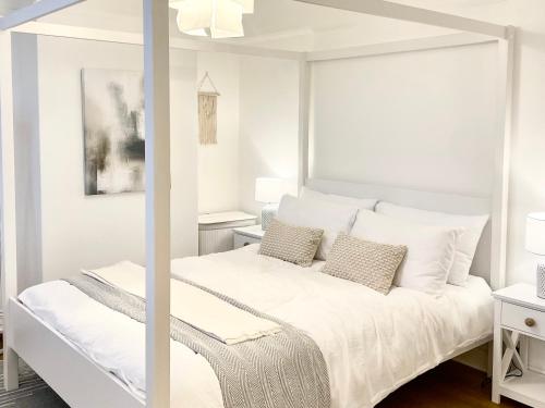 a white bedroom with a white bed with pillows at Windsor Cottage in Amble
