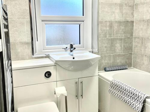 a white bathroom with a sink and a window at Windsor Cottage in Amble