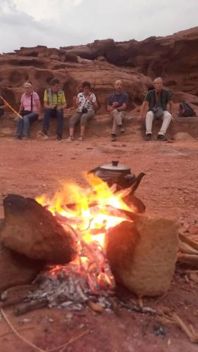 a group of people sitting around a campfire at غرووب وادي رم in Wadi Rum