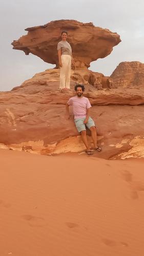 two men sitting on a rock in the desert at غرووب وادي رم in Wadi Rum