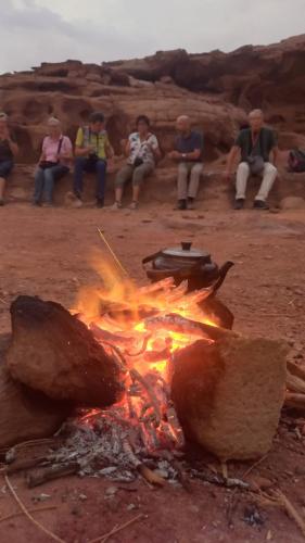 a group of people sitting around a camp fire at غرووب وادي رم in Wadi Rum