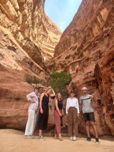 a group of people standing in a canyon at غرووب وادي رم in Wadi Rum