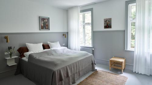 a white bedroom with a bed and two windows at Hotel Ny Hattenæs in Silkeborg
