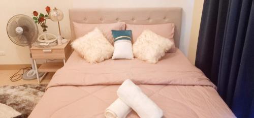 a bedroom with a bed with pink sheets and pillows at Unit 3J Signature Suites, Lafayette Megaworld in Iloilo City