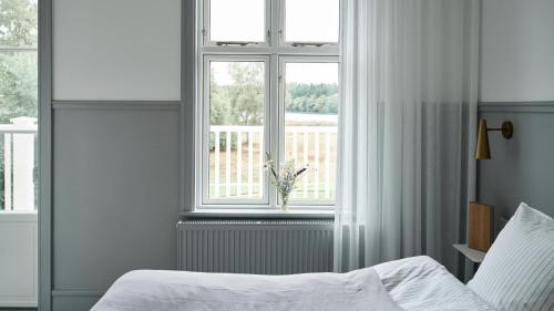 a bedroom with a bed and a window with white curtains at Hotel Ny Hattenæs in Silkeborg