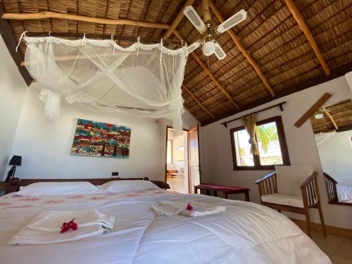 a bedroom with a large white bed with a ceiling at Laguna Blu - Resort Madagascar in Andavadoaka
