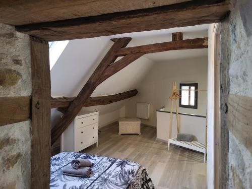 een slaapkamer op zolder met houten balken en een bed bij Appartement au pied du circuit de Magny-cours in Magny-Cours