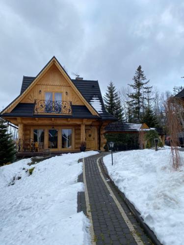 a wooden house with snow in front of it at Willa Górskie Tarasy in Kościelisko