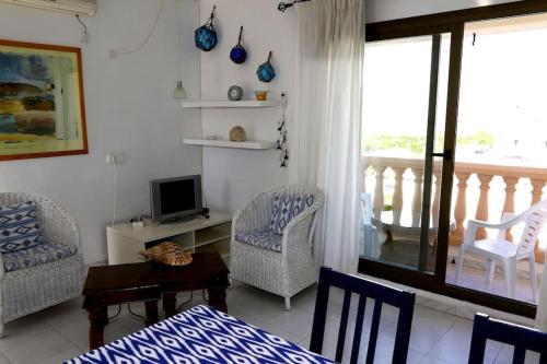 a living room with a bed and chairs and a television at Casa Lago - Formenteralodge in Es Pujols