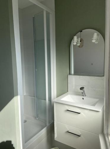 une salle de bain blanche avec un lavabo et une douche dans l'établissement Le petit Villers, à Villers-sur-Mer