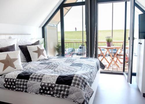 a bedroom with a bed and a balcony with a table at Perlekieker 2 in Büsum