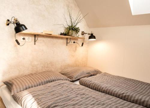 two beds in a bedroom with a shelf on the wall at Achtern Diek in Büsum