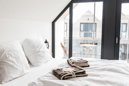 uma cama branca com toalhas por cima em Strandnest em Büsum