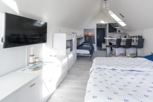 a white bedroom with a bed and a flat screen tv at Steife Brise in Büsum